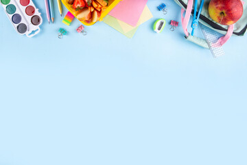 Back to school. Healthy school meal, children packed lunch box with fruit, berry, nuts, sandwich with vegetables. Kids diet snack food with education school supplies, bright blue background top view