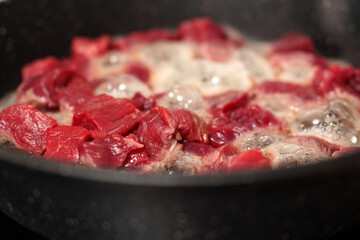 Cooking diced beef in a pan over high heat with bubbling oil and fresh meat pieces
