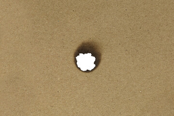 Brown kraft paper texture with a burnt hole in the center, ideal for grunge, vintage, or abstract...
