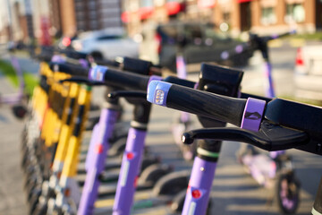 Colorful electric scooters stands parked on a vibrant city sidewalk.