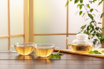 Tasty green tea in glass cups, teapot and leaves on wooden table