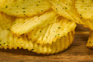 Crunchy potato chips stacked neatly with a golden hue and flecks of seasoning visible in close-up...