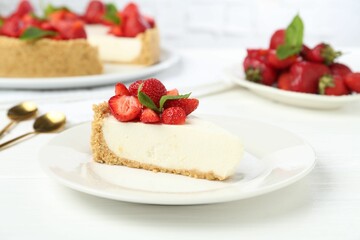 Piece of tasty cheesecake with strawberries and mint on white wooden table, closeup