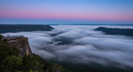 Obraz premium Elevated View of a Canyon at Dawn with Pink and Purple Sky, Thick Fog Rolling Through the Valley