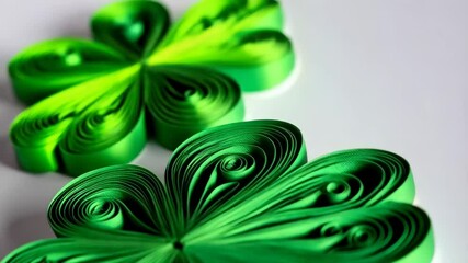 Handcrafted shamrocks made of green paper strips on white surface. Quilled lucky symbols. Paper art project with spiral patterns. Festive decor elements. - Powered by Adobe