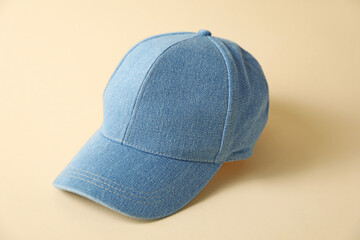 Denim baseball hat on beige background, closeup