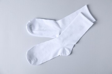 Pair of comfortable white socks on light gray background, top view