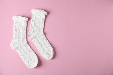 Pair of comfortable white socks on pink background, top view. Space for text