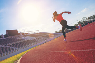 Fit young woman running sprinting at the racetrack. Fit runner fitness runner during outdoor workout at racetrack.