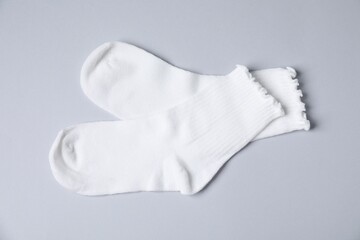 Pair of comfortable white socks on gray background, top view