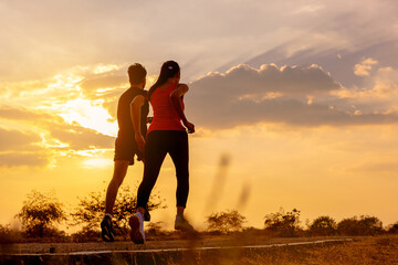Silhouette of young couple running together on road across the bridge. Couple, fit runners fitness runners during outdoor workout