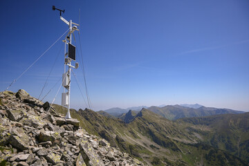 Automated weather station collecting atmospheric data on a remote mountain peak, contributing to...