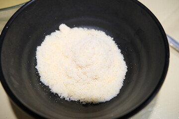 Close-up of finely grated Parmesan cheese served in a black bowl, ideal for cooking, pasta toppings, or food preparation visuals.