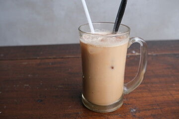 Iced milk coffee in glass mug on wooden table