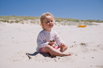 Little Girl Playing Alone in the Sand on the Beach