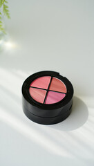 Round makeup palette with four shades of pink blush and coral