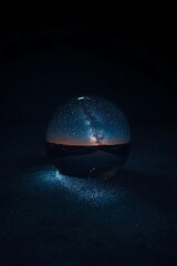 Crystal ball reflecting a stunning desert landscape under the milky way galaxy at twilight with ethereal glow