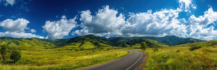 Naklejka premium Winding road cuts through vibrant green hills under a stunning blue sky, a picturesque journey awaits.