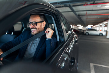 Man Smiling and Buckling Seatbelt Inside Car at Urban Parking Garage