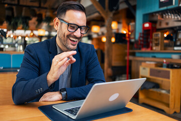 Man Engaged in Video Call at Coffee Shop with Laptop