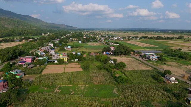 landscape with green fields and blue sky. Wide aerial perspective of rural farming community in Nepal, flat agricultural fields preparing for plantation in Terai region with cloudy horizon