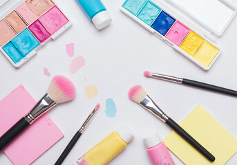 Flatlay of Pastel Watercolor Paints and Black Brush on White Background in Creative Artistic Composition