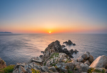 Sunset over Estaca de Bares Galicia rocky headland facing Atlantic calm waves glowing sky massive...