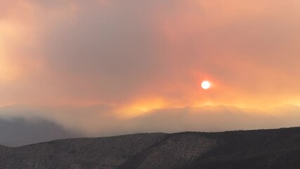Thick smoke rising from the Forsyth wildfire on Pine Valley Mt. Utah USA obscures the sun and swirls in the air drifting with a slight southwest wind as the sun drops below the ridge on June 28 2025.
