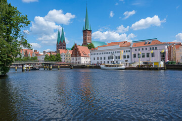 River landscape with boats and historic buildings under a clear blue sky, Lübeck, Schleswig-Holstein, Germany