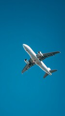 Obraz premium A white passenger airplane flying high in the clear blue sky viewed from below