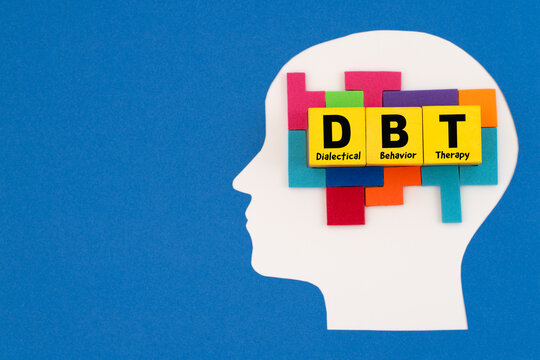 A paper-cut human head with yellow blocks labeled 'DBT' surrounded by puzzle pieces, symbolizing the therapeutic tools used to piece together emotional regulation and personal growth