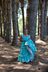 A beautiful young Spanish woman dressed in a traditional green flamenco dress with a flower in her...