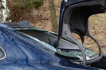 Wreck of car with broken window and open trunk, victim of theft
