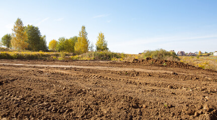 Empty land plot with tire prints prepared for new housing in rural area. Clearing and leveling of...
