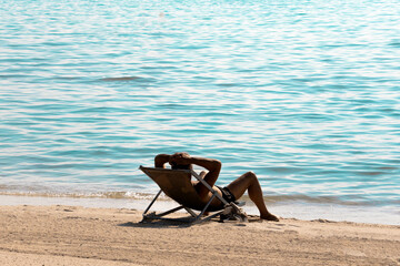 homme bronzant sur une chaise longue sur une plage