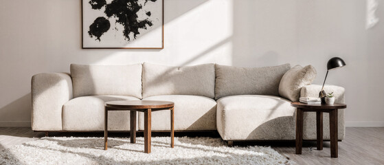 A soft cream-colored curved sofa, white walls, and a walnut-colored side table with an abstract design.
