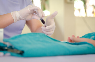 Nurse wearing white medical gloves is drawing blood from patient's arm for examination or PRP procedure. Concept of laboratory research, medicine, analysis.
