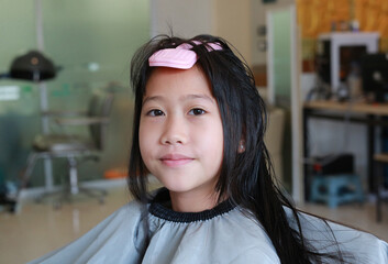 Asian preteen girl having her hair cut. Child sitting in beauty hair salon style for children....