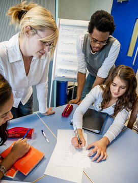 Teenage Students: Teaching Supervision. A group of students working together on a group project with their teacher watching on. From a series of related images.