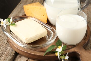 Different fresh dairy products and flowers on wooden table, closeup