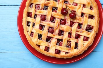 Tasty cherry pie on light blue wooden table, top view
