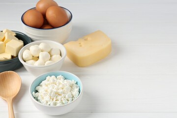 Different dairy products and eggs on white wooden table, closeup. Space for text