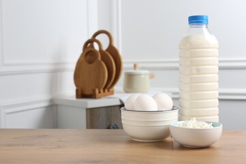 Different dairy products and eggs on wooden table indoors. Space for text