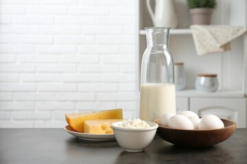 Different dairy products and eggs on gray textured table in kitchen