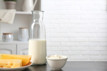 Different dairy products on gray textured table in kitchen. Space for text