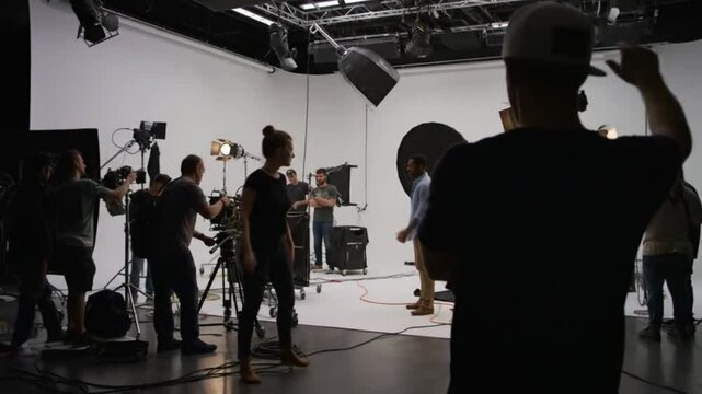 Behind-the-scenes view of a film production team setting up a shoot in a professional studio, showcasing collaborative work and essential equipment...
