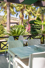 Outdoor dining area with white furniture surrounded by lush greenery and tropical plants