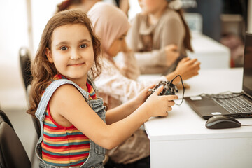 Little girl using joystick in a classroom. Concept of technological modern education.