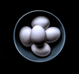 Eggs in blue bowl on black background