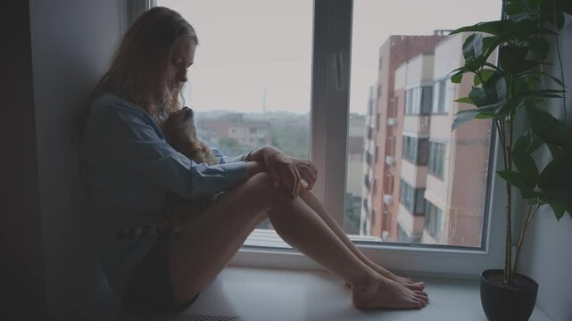 Unhappy beauty woman crying sitting on the windowsill window rain drops falling dark rainy weather mood depression sadness loneliness emotion at home. Adult upset Girl sad face. hand holds pet cat 4k